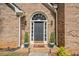 Close up of arched entryway with slate gray door, brick facade, and potted greenery at 8035 Canter Ln, Alpharetta, GA 30009