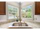 Kitchen sink with gooseneck faucet set in granite countertops below corner windows with views of trees at , Marietta, GA 30064