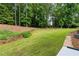 Expansive backyard with a lush lawn, mature trees, stone retaining walls, and well-maintained landscaping at 130 Robin Rd, Marietta, GA 30067