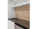 Close-up of a wet bar area featuring a dark granite countertop, tile backsplash, and wine rack at 130 Robin Rd, Marietta, GA 30067