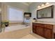 Bathroom with soaking tub under window, glass shower, tile surround, and wooden vanity at 103 Old Avery Dr, Canton, GA 30115