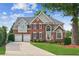 Inviting two-story brick home with a well-manicured lawn, two-car garage, and charming landscaping at 1316 Wind Chime Ct, Lawrenceville, GA 30045