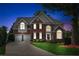 Well-maintained two-story brick home with a manicured lawn, two-car garage, and inviting front entrance at twilight at 1316 Wind Chime Ct, Lawrenceville, GA 30045