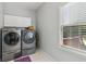 Functional laundry room with washer, dryer, overhead cabinets, and natural light at 1316 Wind Chime Ct, Lawrenceville, GA 30045