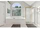Bright main bathroom with a soaking tub, glass shower, and large decorative window at 1316 Wind Chime Ct, Lawrenceville, GA 30045