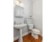 Elegant powder room featuring a pedestal sink, decorative mirror, and hardwood floors at 1316 Wind Chime Ct, Lawrenceville, GA 30045