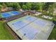 Aerial view of multiple community tennis courts, featuring blue courts, black fencing, and a covered gazebo seating area at 1316 Wind Chime Ct, Lawrenceville, GA 30045