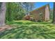 Expansive backyard featuring a brick house with a wooden deck surrounded by lush trees and vibrant green grass at 3592 Midvale Cv, Tucker, GA 30084