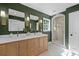 A modern bathroom features a dual sink vanity, accent mirrors, green walls, and a large walk-in shower at 5143 Meadowlake Ln, Dunwoody, GA 30338