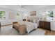 A bright bedroom features hardwood floors, neutral colors, a ceiling fan, and windows with a bench at the foot of the bed at 5143 Meadowlake Ln, Dunwoody, GA 30338