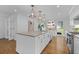 Modern white kitchen with a large center island, stainless steel appliances, and hardwood floors at 5143 Meadowlake Ln, Dunwoody, GA 30338