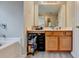 Bathroom with wood cabinets featuring a large mirror, double sink, and a tub at 1171 Pine Acre Dr, Sugar Hill, GA 30518