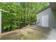 Concrete back patio offers an outdoor space with wooded backdrop, door to home and utility access at 3379 Thornbridge Dr, Powder Springs, GA 30127