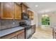 Traditional kitchen with wood cabinets, tile backsplash, black appliances, and dining area beyond at 3379 Thornbridge Dr, Powder Springs, GA 30127