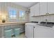 Bright laundry room with patterned wallpaper, modern appliances, overhead cabinets, and natural light at 4779 Bogan Meadows Dr, Buford, GA 30519