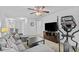 Comfortable living room area featuring a cozy grey couch, modern TV, and a stationary bike next to the large window at 4779 Bogan Meadows Dr, Buford, GA 30519