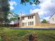 A backyard with a two story home, a pool, trees, grass, a patio, and a wooden fence at 6005 Pattingham Dr, Roswell, GA 30075