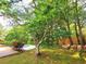 A view of a covered pool, green grass, trees, bushes, and a wooden fence on a sunny day at 6005 Pattingham Dr, Roswell, GA 30075