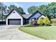 Charming single-story home featuring a brick facade, black trim, landscaped yard, and a driveway leading to a two-car garage at 2190 Ashley Crossing Ct, Lawrenceville, GA 30043