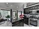Open kitchen with island, stainless steel appliances, dark cabinets, and bright windows overlooking backyard at 2190 Ashley Crossing Ct, Lawrenceville, GA 30043