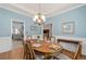 Formal dining room with hardwood floors, crown molding, chandelier, and views into an adjacent kitchen at 3027 Biltmore Woods Dr, Buford, GA 30519