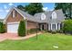 Charming brick home with lush lawn, mature trees, and a brick driveway leading to a two-car garage at 567 N Palisades Se Cir, Marietta, GA 30067