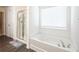 Clean bathroom featuring a separate shower and soaking tub with tiled walls, a large window and modern fixtures at 668 Isom Walk, Suwanee, GA 30024