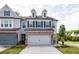 Beautiful townhome exterior with a two-car garage, a brick facade, and a well-maintained lawn at 668 Isom Walk, Suwanee, GA 30024