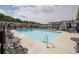 Community pool surrounded by seating and townhome-style architecture on a sunny day with scattered clouds at 668 Isom Walk, Suwanee, GA 30024