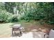 Relaxing backyard area with a grill, surrounded by lush greenery and mature trees at 1000 Willow Crest Lndg, Austell, GA 30168