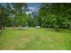 Vast backyard showing a swimming pool, shed, playset, and lush green grass surrounded by mature trees at 1565 Wynfield Dr, Auburn, GA 30011