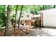 View of home's backyard with brick and white exterior, wooden deck and a curved brick pathway surrounded by mature trees at 2620 Clairmont Rd, Atlanta, GA 30329