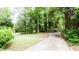 View of home's front yard with green grass, mature trees and a curved driveway at 2620 Clairmont Rd, Atlanta, GA 30329