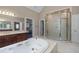 Elegant bathroom featuring a jacuzzi tub, glass enclosed shower, and vanity with decorative fixtures at 11569 Finley St, Suwanee, GA 30024