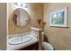 Charming powder room features a decorative sink, wallpaper, and round mirror at 11569 Finley St, Suwanee, GA 30024