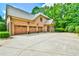 A stunning brick home with a three-car garage and a meticulously maintained front yard featuring mature trees at 2111 Broadfield Run, Duluth, GA 30097