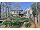 Back exterior view of home featuring a wooden deck, steps, and lush garden with blooming white flowers at 3075 Superior Dr, Dacula, GA 30019