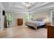 Expansive main bedroom showcasing hardwood floors, a tray ceiling, a ceiling fan, and three large windows at 3962 Coventry Park Ln, Peachtree Corners, GA 30096