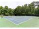 Outdoor tennis court surrounded by lush trees, perfect for recreational play at 1221 Fountain Head Ct, Lawrenceville, GA 30043
