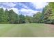 Vast backyard with a perfectly manicured lawn surrounded by mature trees, offering privacy and a natural setting at 4809 Highland Point Dr, Auburn, GA 30011