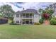 Rear exterior view of the home featuring a balcony, covered patio, well-manicured lawn, and lush landscaping at 4809 Highland Point Dr, Auburn, GA 30011
