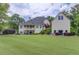 Back exterior showcasing a well-maintained lawn, the main house, and a detached garage surrounded by mature trees at 4809 Highland Point Dr, Auburn, GA 30011