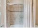 Close-up on neutral toned tiled shower with glass door and decorative mosaic tile accent at 4809 Highland Point Dr, Auburn, GA 30011