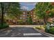 Exterior of brick condominium building with sidewalks, mature trees, manicured landscaping, and a stop sign at 2300 Peachford Rd # 3411, Dunwoody, GA 30338