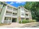 Exterior view of the green apartment building with white balconies and well-maintained landscaping at 328 Bentley Pl # 328, Tucker, GA 30084