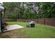 Grassy backyard featuring a grill, patio area, and a wooden fence surrounded by tall trees at 7113 Silver Mine Xing, Austell, GA 30168