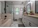 This bathroom has a walk-in shower, bathtub, a double vanity, white cabinets, and a herringbone tile design at 7113 Silver Mine Xing, Austell, GA 30168