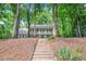 Elegant two-story home with a double balcony nestled among mature trees, accessed by a wooden staircase at 3870 Windhurst Dr, Lilburn, GA 30047