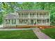 Charming two-story home featuring double balconies, a brick foundation, and lush landscaping at 3870 Windhurst Dr, Lilburn, GA 30047