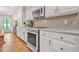 Bright kitchen with white cabinets, stainless steel appliances, marble countertops and backsplash at 3870 Windhurst Dr, Lilburn, GA 30047